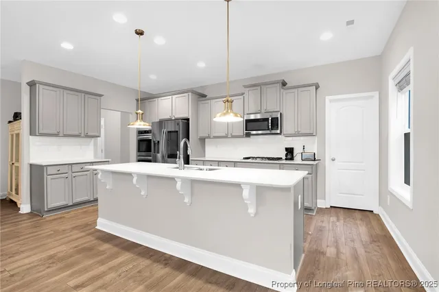 a kitchen with kitchen island a sink a stove a refrigerator cabinets and a wooden floor