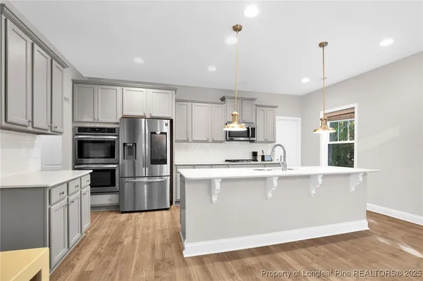 a large kitchen with cabinets wooden floor and stainless steel appliances