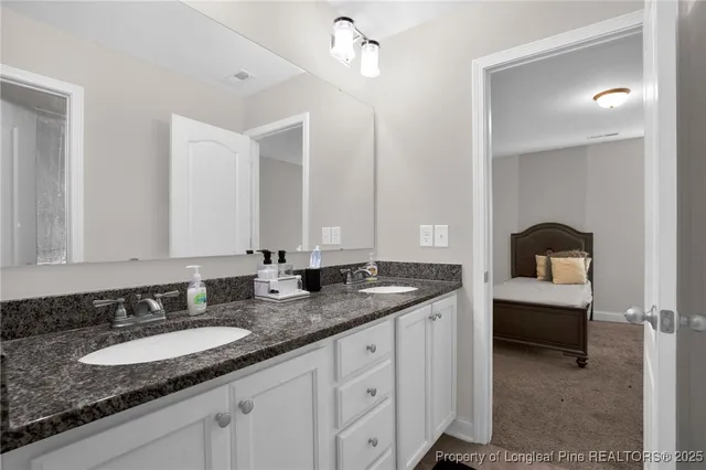 a bathroom with a granite countertop double vanity sink and mirror