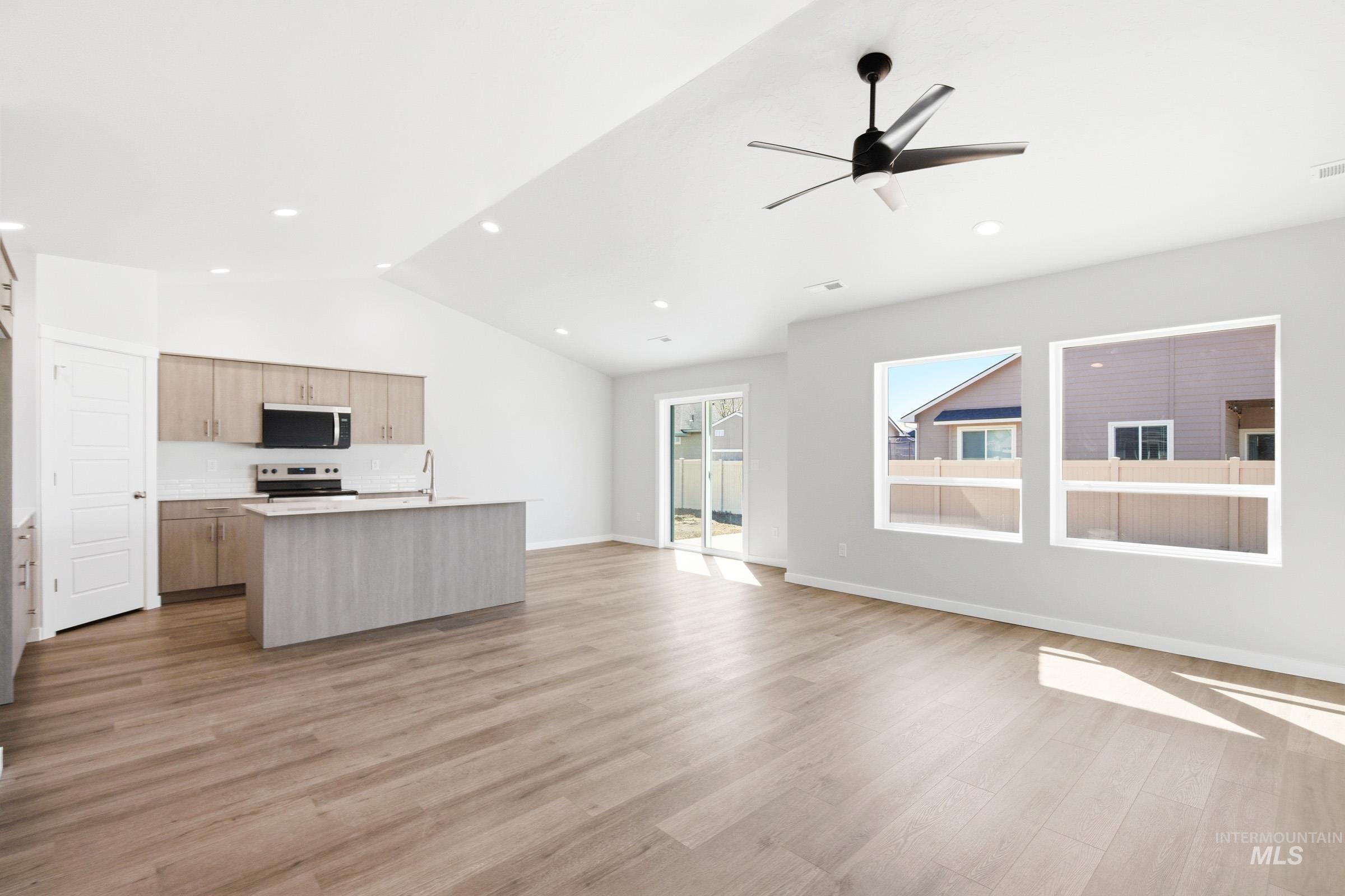 12877 Decatur Street Nampa, ID 83651 - Photo 13 of 22 Open-concept living area featuring wood-finish flooring, a vaulted ceiling, and a contemporary ceiling fan
