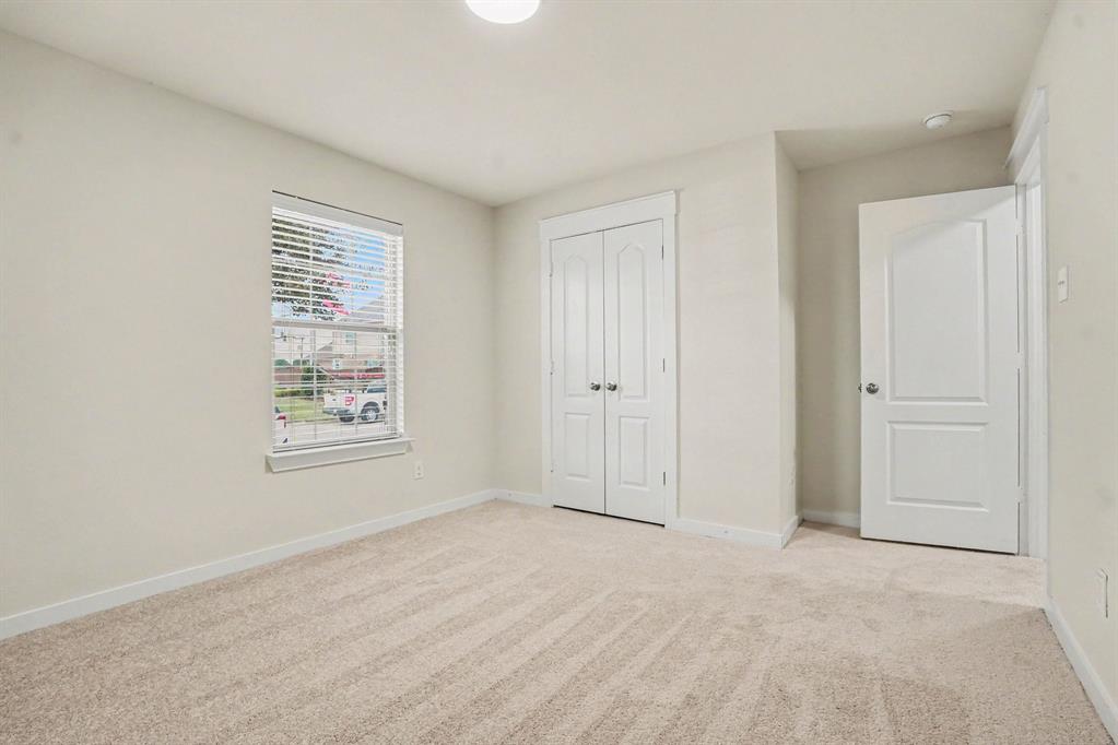 2606 Middleton Road Glenn Heights, TX 75154 - Photo 14 of 18 Bedroom 2- Neutral carpet flooring, a window with blinds, a built-in closet with double doors, and a flush-mount ceiling light fixture