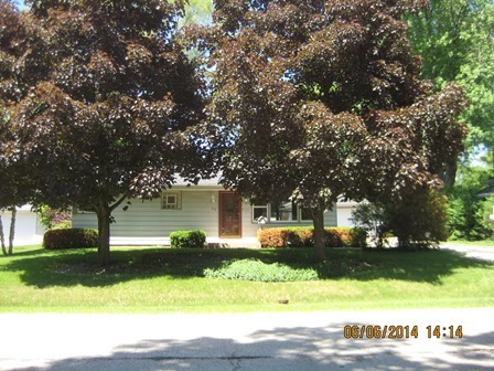 a view of a white house with a big yard and large tree