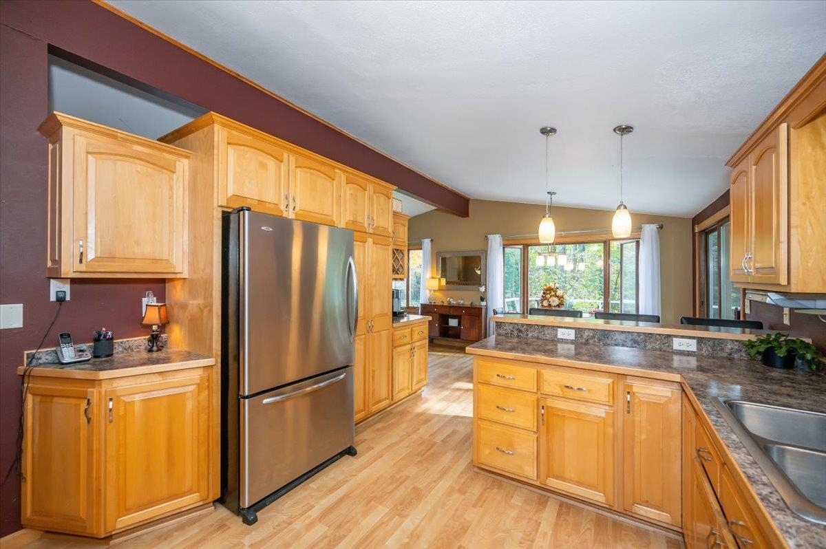 6891 South Oakland Road Superior, WI 54880 - Photo 6 of 29 Kitchen with freestanding refrigerator, pendant lighting, a peninsula, light wood-type flooring, and tile countertops