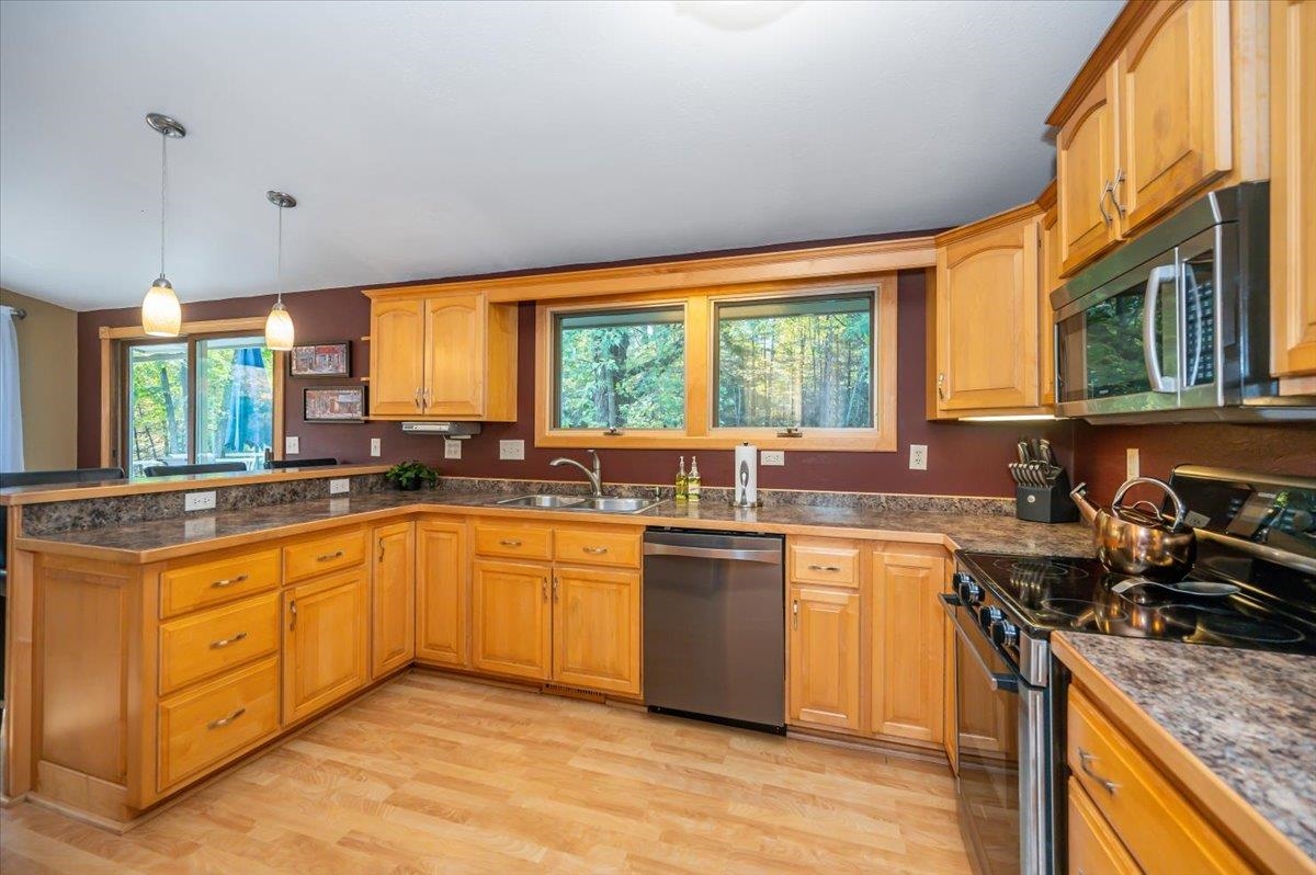 6891 South Oakland Road Superior, WI 54880 - Photo 7 of 29 Kitchen featuring stainless steel appliances, pendant lighting, light wood finished floors, a peninsula, and tile counters