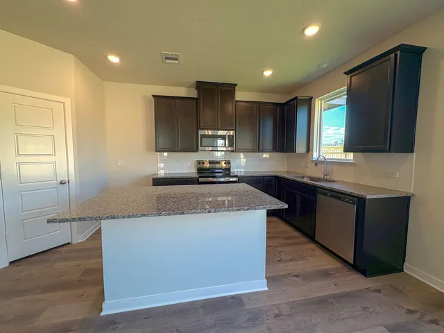 a kitchen with kitchen island granite countertop wooden cabinets a sink and a stove