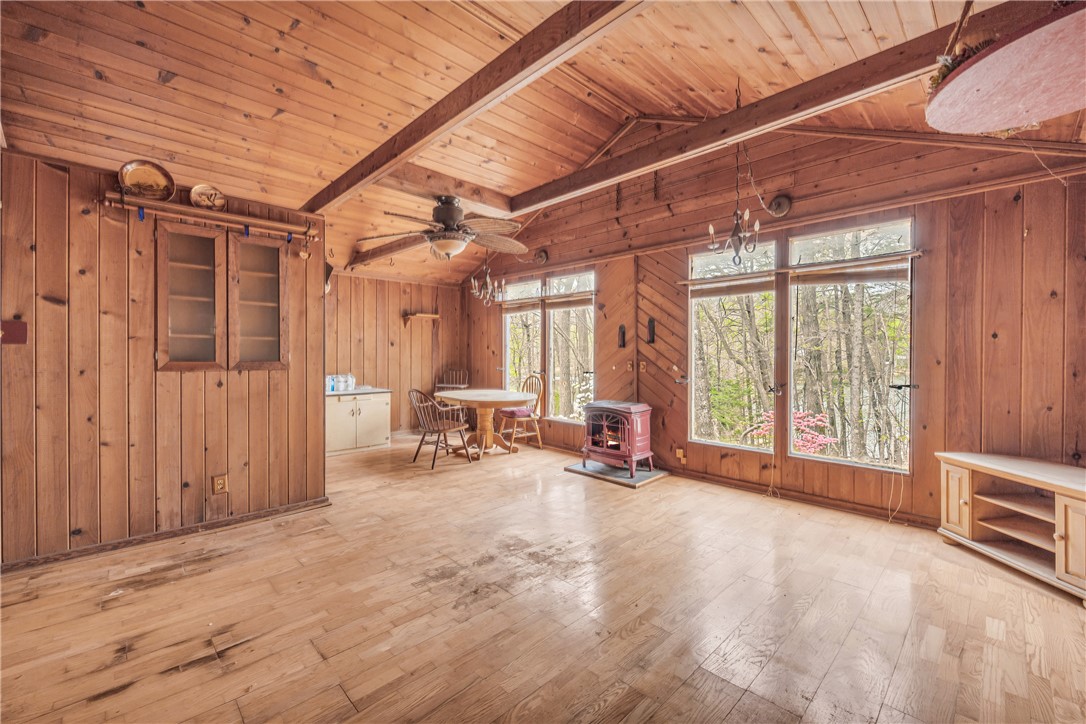 115 Little Stakey Rd Mountain Rest Mountain Rest, SC 29664 - Photo 5 of 38 This living space features warm wood paneling, expansive windows, and a classic wood stove, perfect for cozy gatherings.