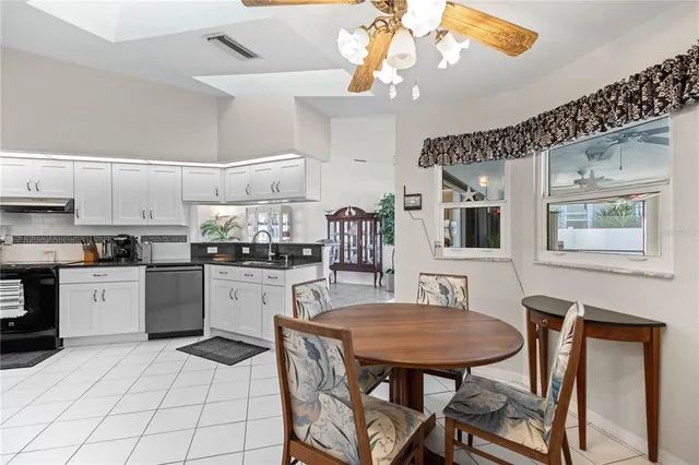 a kitchen with stainless steel appliances a sink a stove a dining table and chairs