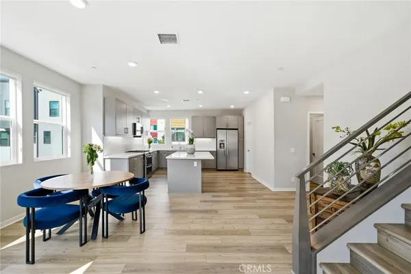 a kitchen with stainless steel appliances a dining table chairs refrigerator and sink