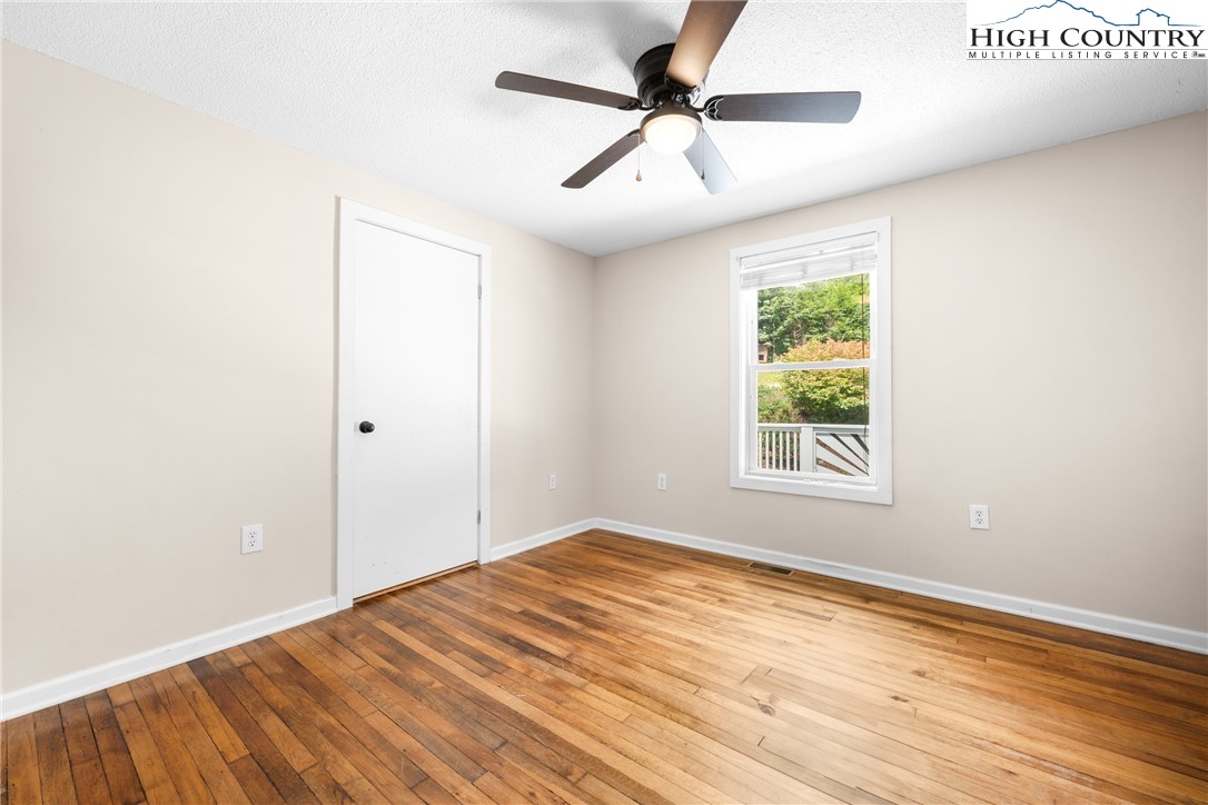261 Tumbling Brook Road Banner Elk, NC 28604 - Photo 26 of 39 an empty room with wooden floor fan and windows