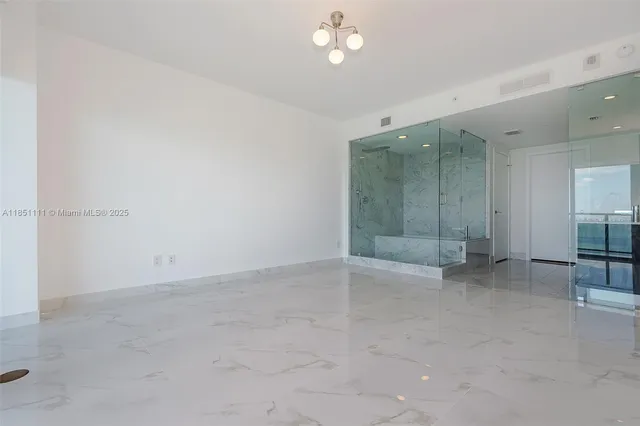 an empty room with chandelier fan and windows