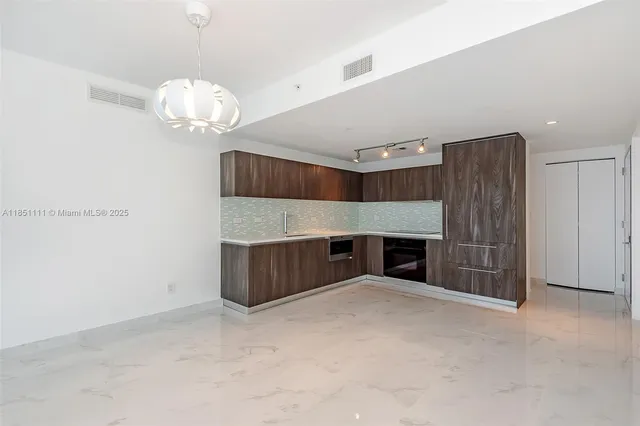 an empty room with a fireplace and chandelier