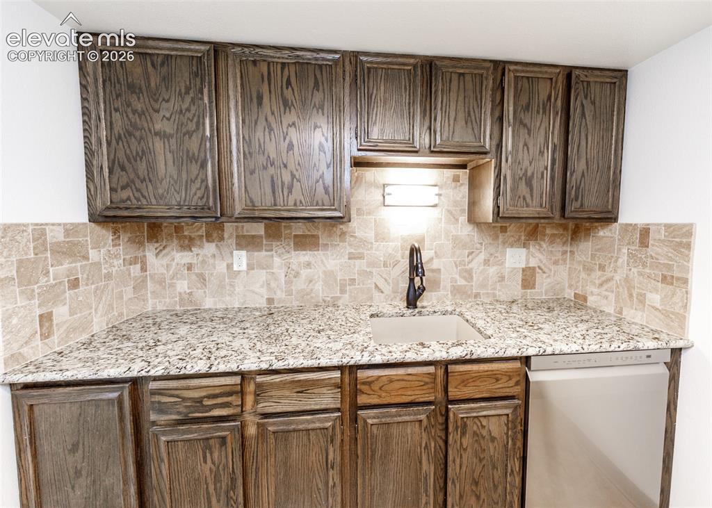1034 Fontmore Road, Unit D Colorado Springs, CO 80904 - Photo 18 of 43 a kitchen with granite countertop wooden cabinets a sink and dishwasher