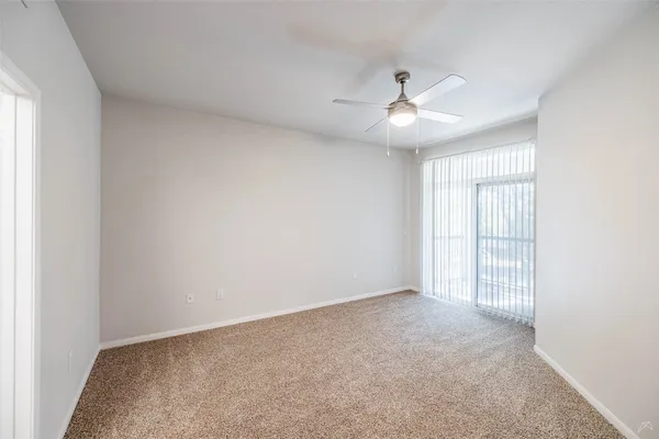 an empty room with chandelier fan and windows