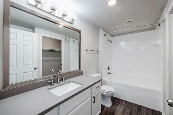 a bathroom with a granite countertop sink toilet a large mirror a bathtub and shower