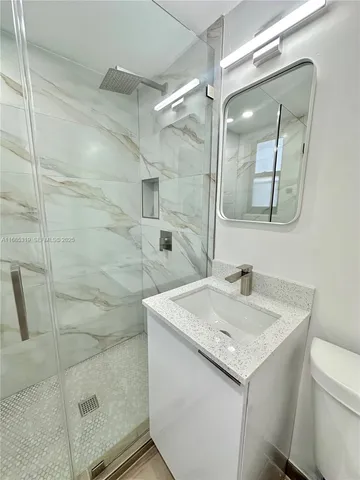 a bathroom with a granite countertop sink a mirror and shower