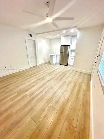 a view of a room with wooden floor and a ceiling fan