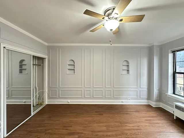 an empty room with wooden floor closet and windows