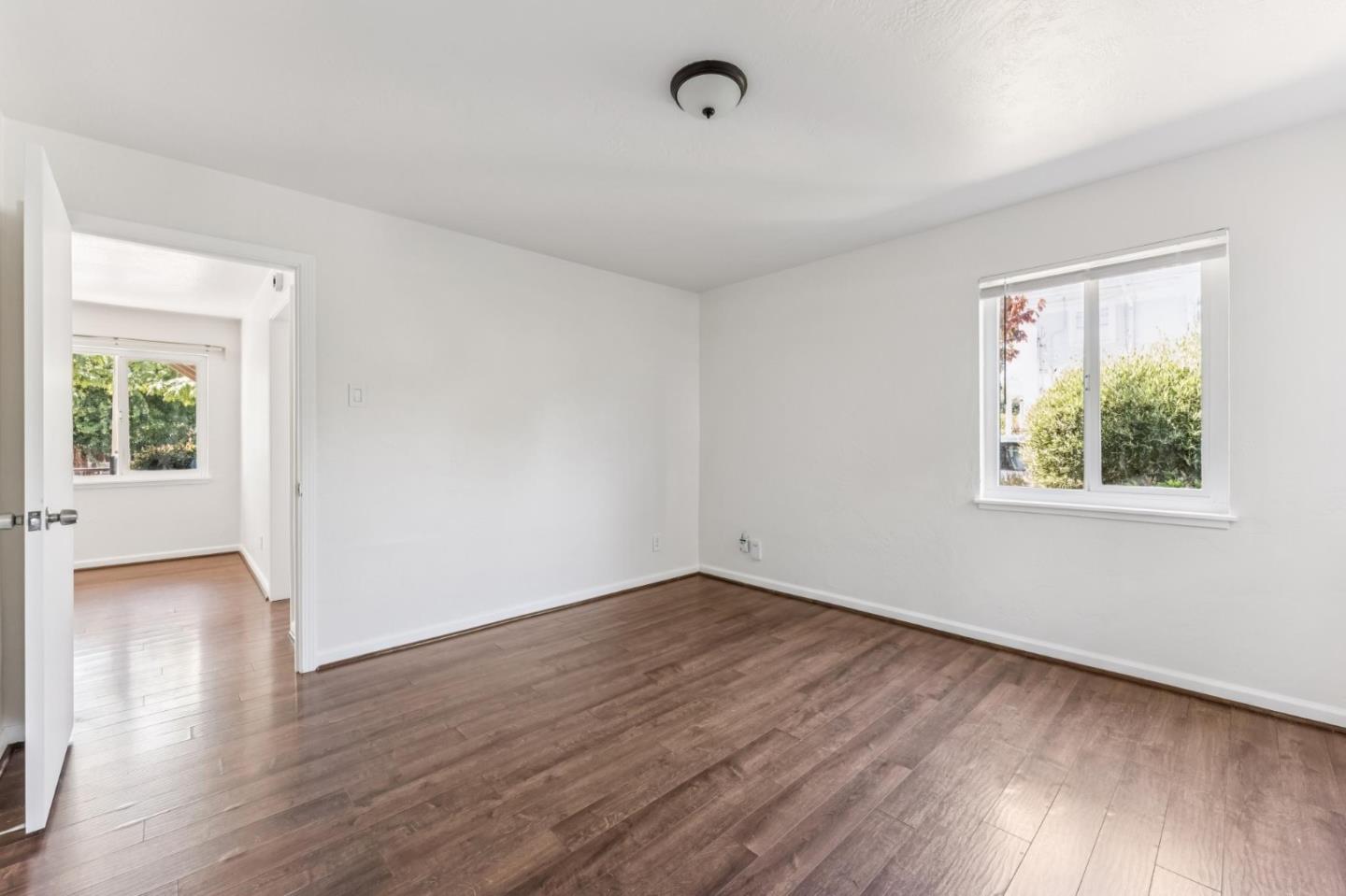 5664 Gaskill Street Oakland, CA 94608 - Photo 12 of 16 an empty room with wooden floor and windows