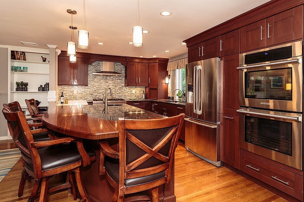 17 Dennett Road Winchester, MA 01890 - Photo 9 of 41 a kitchen with stainless steel appliances kitchen island granite countertop a stove a refrigerator a microwave oven a dining table and chairs with wooden floor