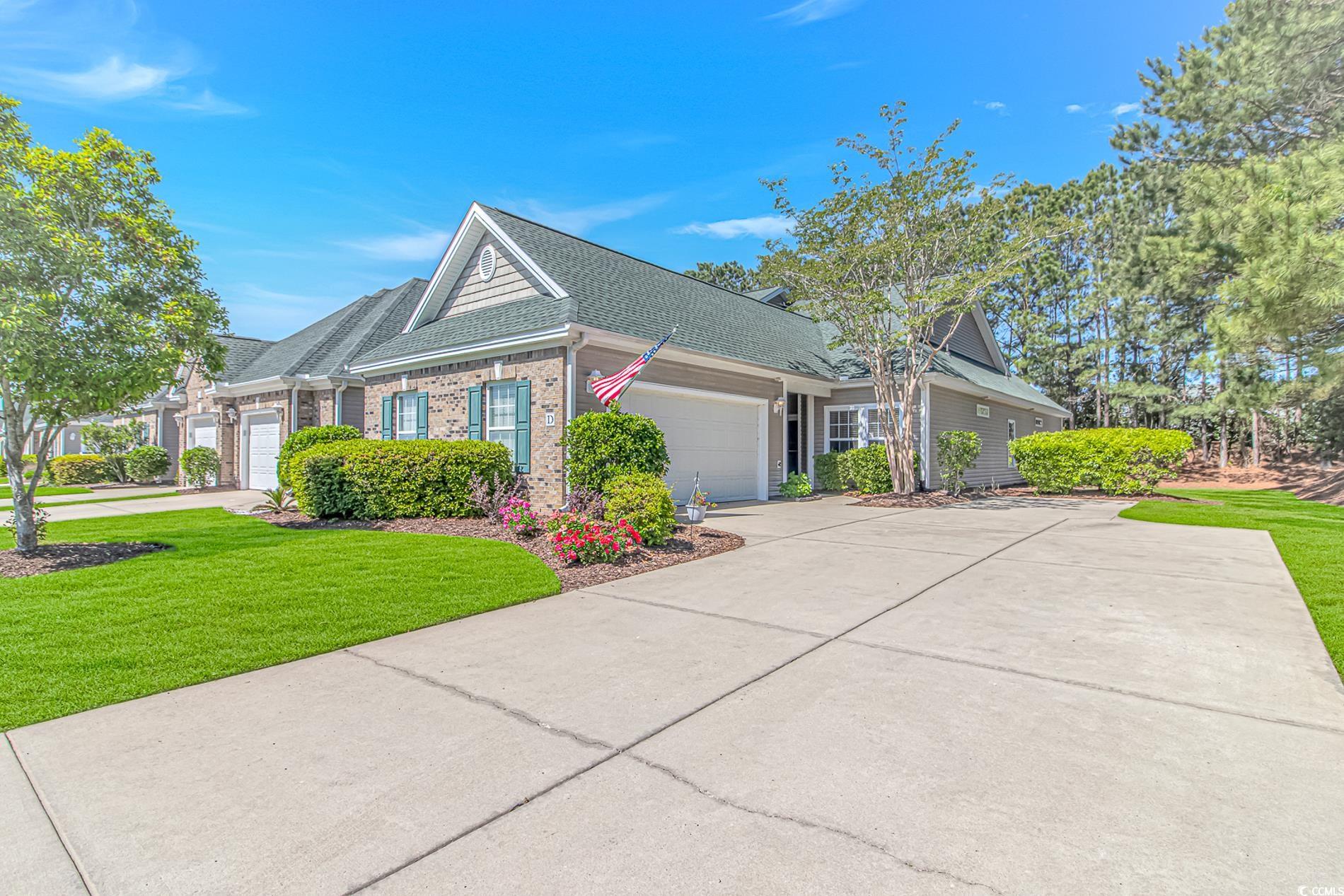 139 Chenoa Drive, Unit D Murrells Inlet, SC 29576 - Photo 30 of 34 View of side of property featuring a garage, a shingled roof, a lawn, and brick siding