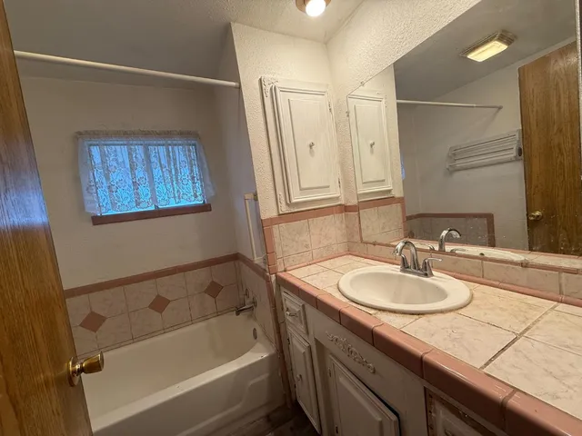 a bathroom with a granite countertop sink mirror vanity and bathtub
