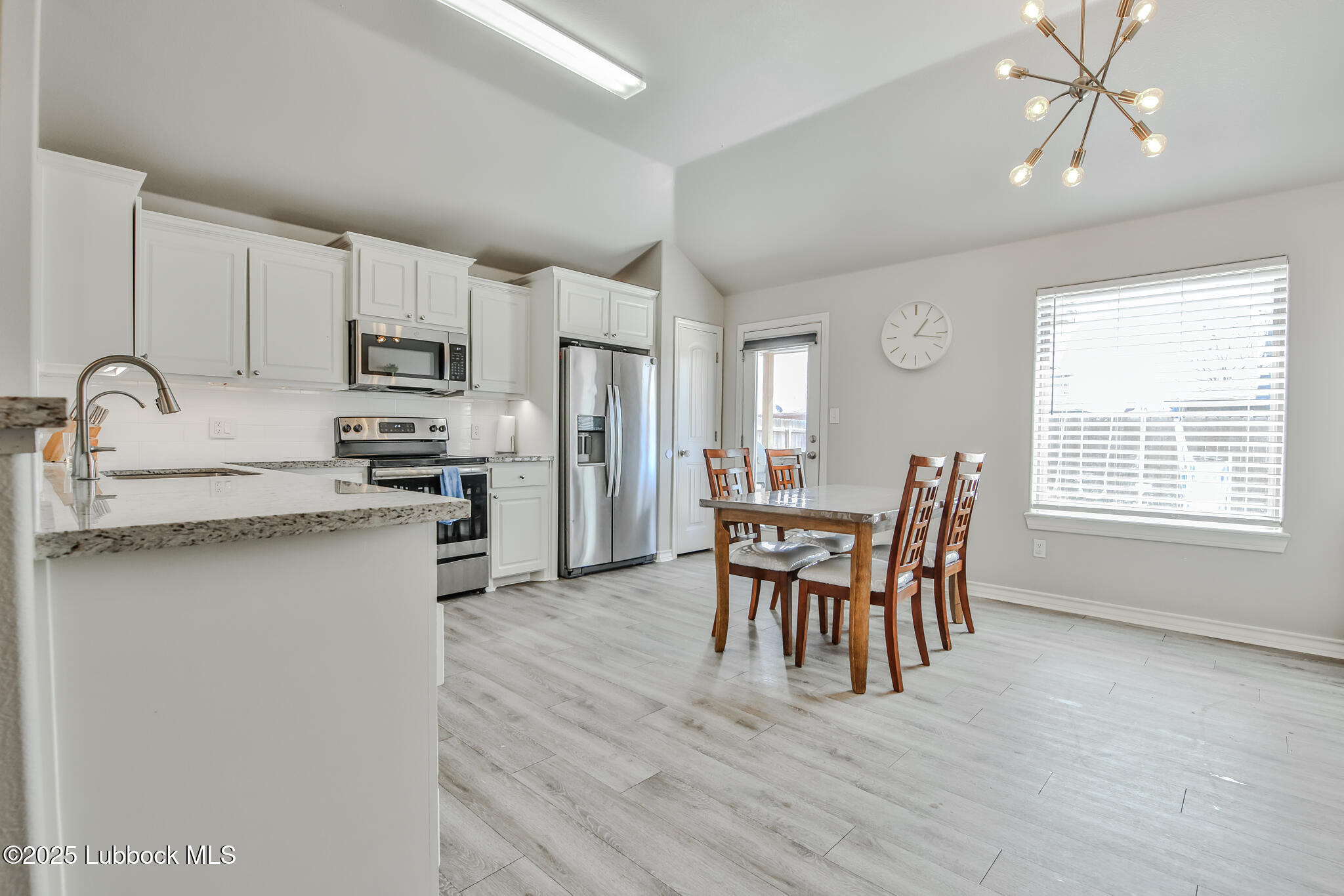 5221 Jarvis Street Lubbock, TX 79416 - Photo 20 of 22 a kitchen with stainless steel appliances granite countertop a stove top oven a sink a dining table and chairs with wooden floor