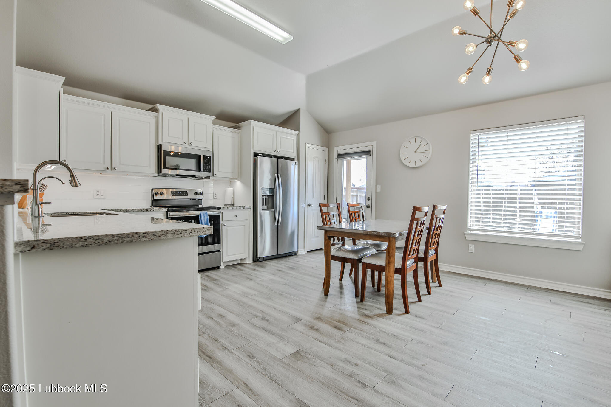 5221 Jarvis Street Lubbock, TX 79416 - Photo 21 of 22 a kitchen with stainless steel appliances granite countertop a stove top oven a sink a dining table and chairs with wooden floor