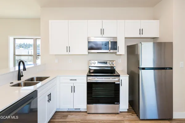 a kitchen with white cabinets and stainless steel appliances