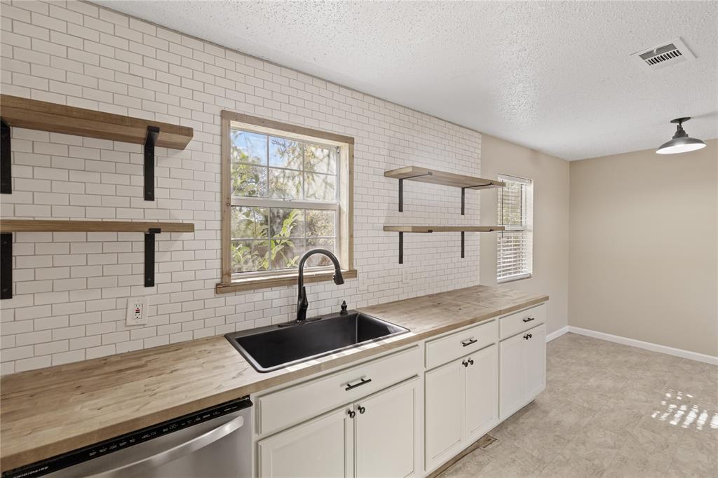 6063 Meandering Road Fort Worth, TX 76114 - Photo 1 of 1 Kitchen with white cabinets, sink, and wooden counters