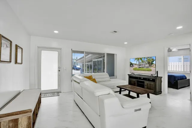 a living room with furniture flat screen tv and windows