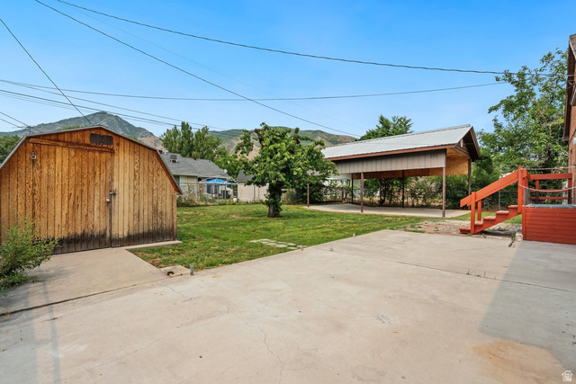 673 East 700 South Springville, UT 84663 - Photo 43 of 43 Expansive concrete patio with a detached wooden barn, a covered carport structure, and a vibrant green lawn