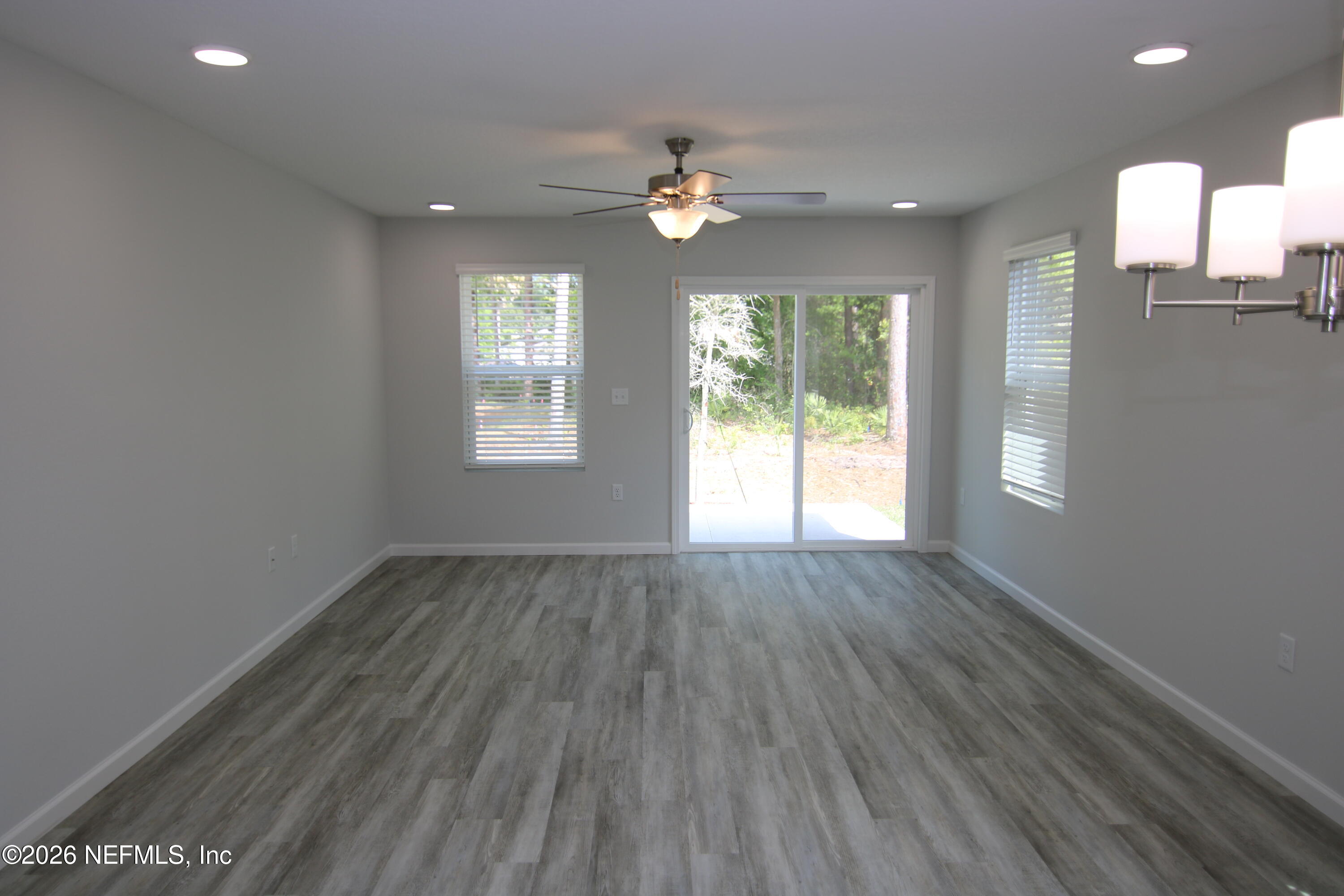 853 Jackson Road Jacksonville, FL 32225 - Photo 3 of 18 an empty room with wooden floor chandelier fan and windows