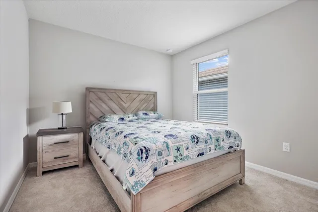 a bedroom with a bed next to a window and a lamp