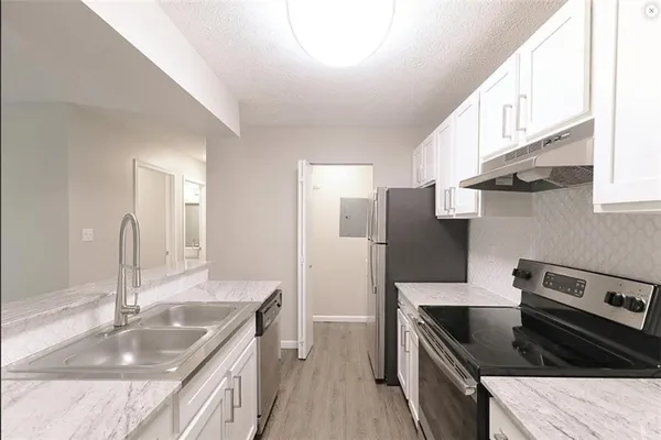 a kitchen with granite countertop a sink stove and refrigerator