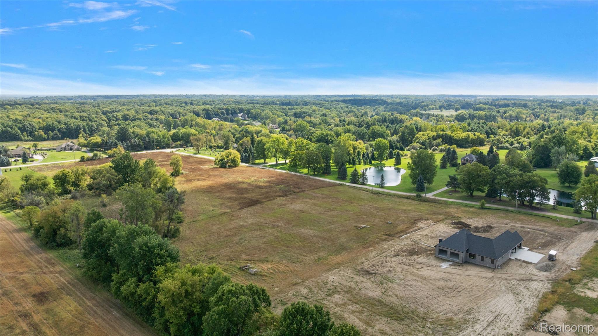4059 Taft Road Romeo, MI 48065 - Photo 14 of 59 Newly constructed residence with a dark gray roof, situated on a large lot with surrounding trees and a visible pond