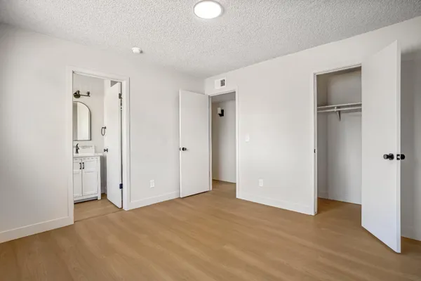 a view of an empty room with closet and wooden floor