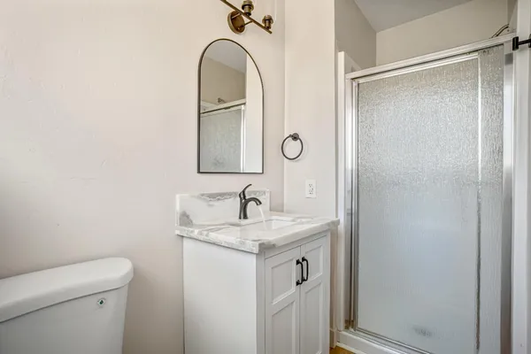 a bathroom with a granite countertop sink toilet and a mirror