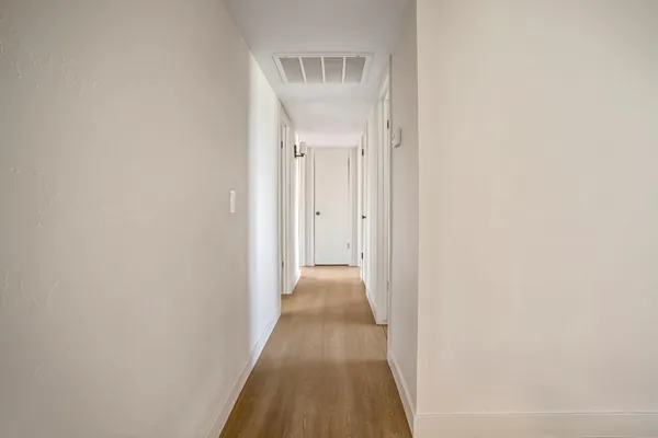 a view of a hallway with wooden floor and a bathroom