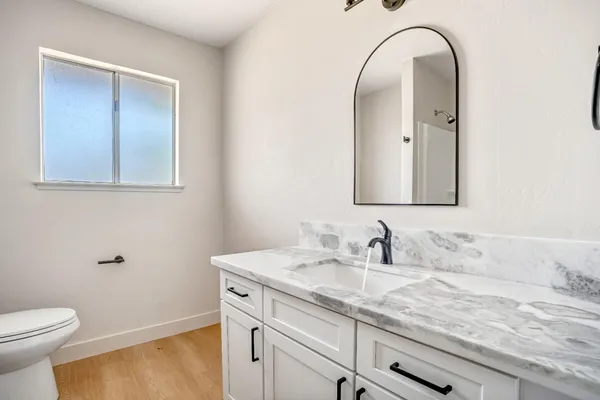 a bathroom with a granite countertop sink a toilet and a mirror