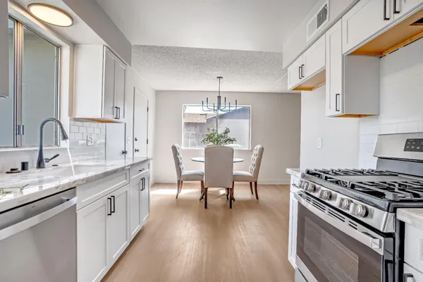 a kitchen with stainless steel appliances a white table chairs and a stove