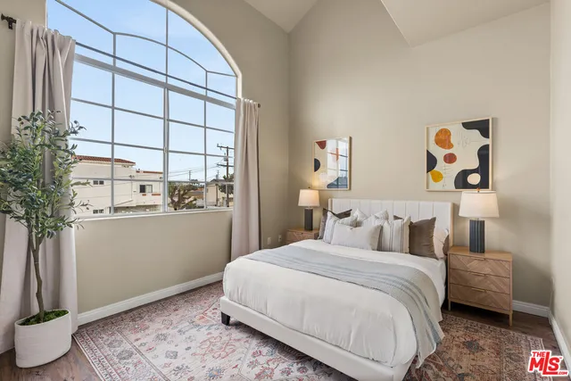 a bedroom with a bed and a window with potted plants