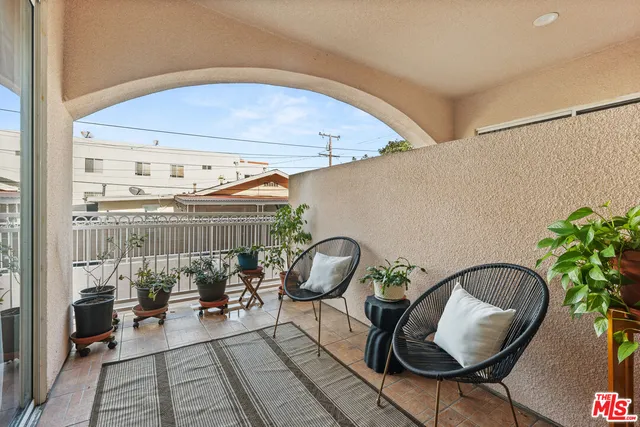 a balcony with chairs and potted plants