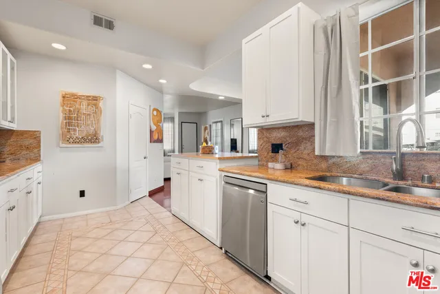 a kitchen with granite countertop a sink window and cabinets