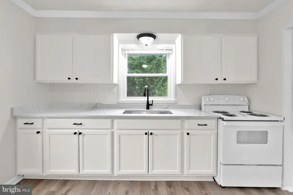 a kitchen with white cabinets appliances and a window