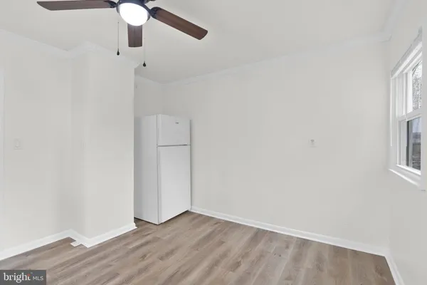 an empty room with wooden floor fan and windows