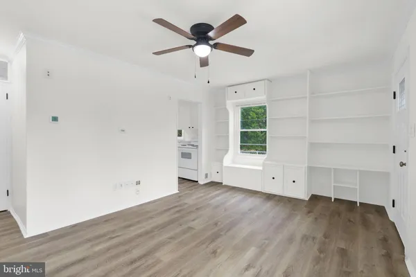 an empty room with wooden floor chandelier fan and windows