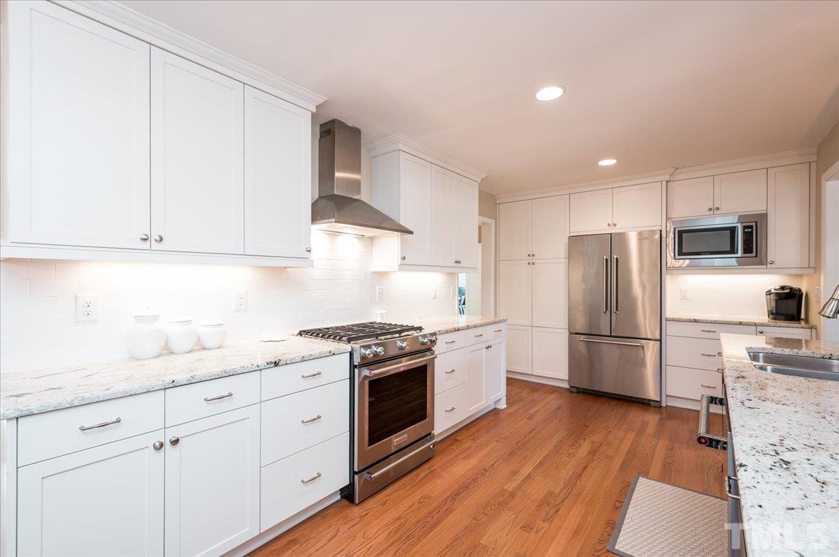 3426 Redbud Lane Raleigh, NC 27607 - Photo 8 of 30 a kitchen with white cabinets and stainless steel appliances