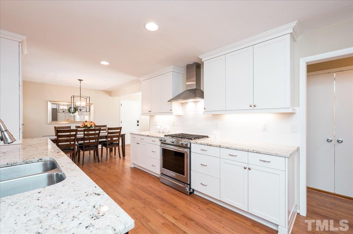 3426 Redbud Lane Raleigh, NC 27607 - Photo 10 of 30 a kitchen with granite countertop a stove top oven a sink a dining table and chairs with wooden floor