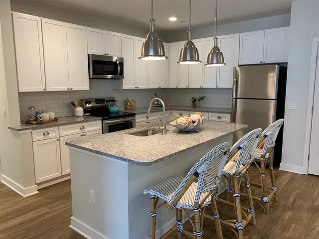 a kitchen with stainless steel appliances granite countertop a stove a refrigerator a sink a dining table and chairs with wooden floor