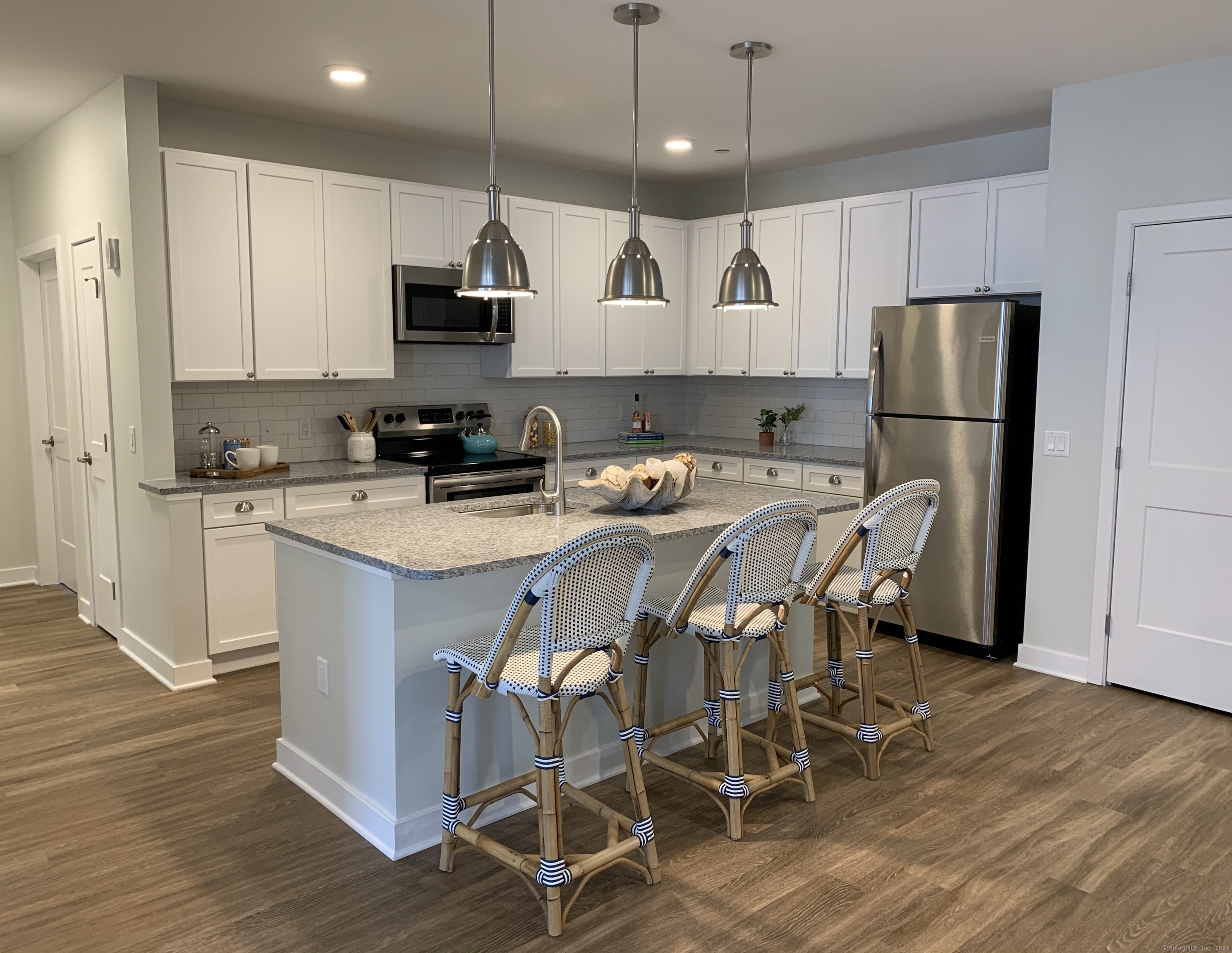 50 Perkins Farm Drive, Unit PH402 NEWPORT Stonington, CT 06355 - Photo 21 of 31 a kitchen with stainless steel appliances granite countertop a stove a refrigerator a sink a dining table and chairs with wooden floor